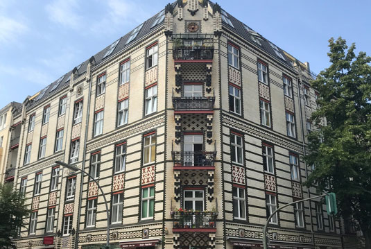 Eckhaus mit auffälliger Fassade aus schwarz-weißen Ziegelmustern und roten Akzenten.